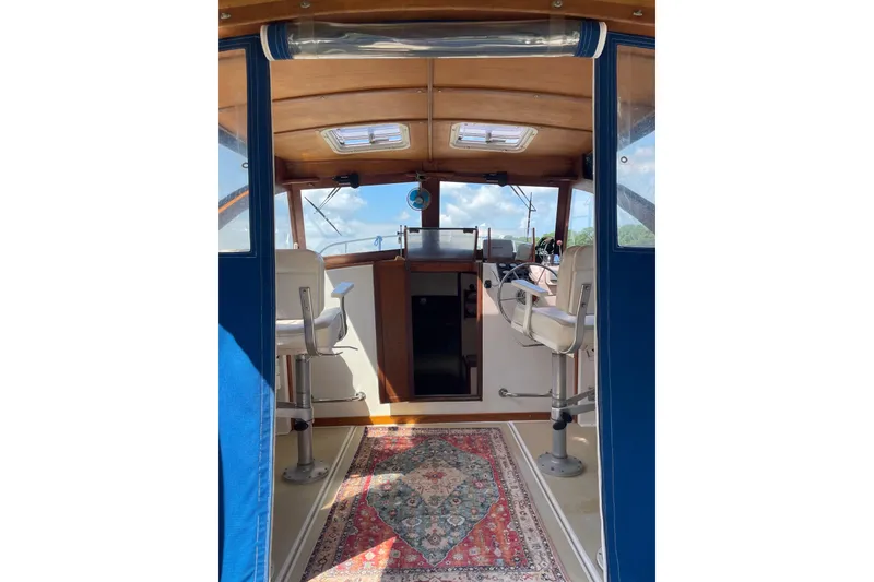 Slide: The Image of 1988 Cape Dory Hardtop interior with helm, seating, and decorative rug. - 19