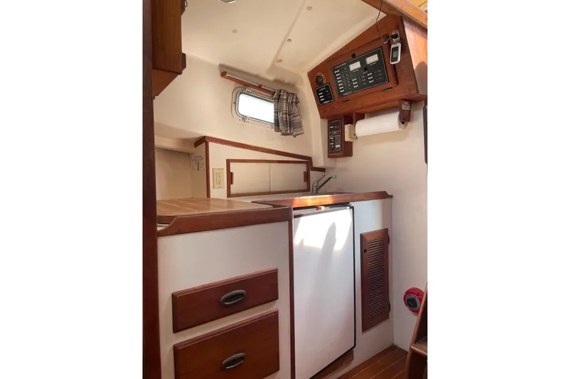 Slide: The Image of 1988 Cape Dory Hardtop interior with kitchenette, wooden cabinetry, and control panel. - 21