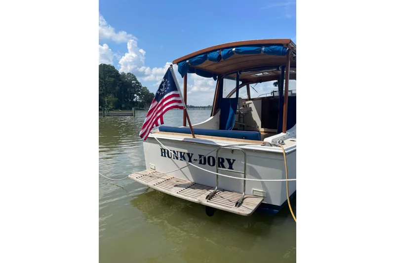 Slide: The Image of 1988 Cape Dory Hardtop boat with American flag on calm water. - 3