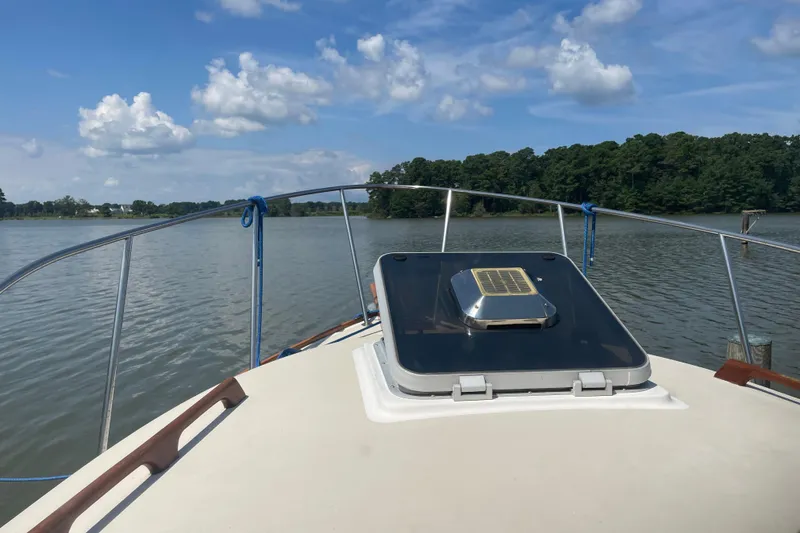 Slide: The Image of 1988 Cape Dory Hardtop boat on calm water under a blue sky with clouds. - 8