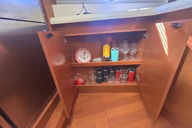 Slide: The Image of Open cabinet on Beneteau Gran Turismo 44 yacht, displaying glasses and nautical-themed plates. - 23