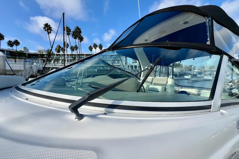 Slide: The Image of 2004 Sea Ray 320 Sundancer boat docked, featuring sleek windshield and marina backdrop. - 11