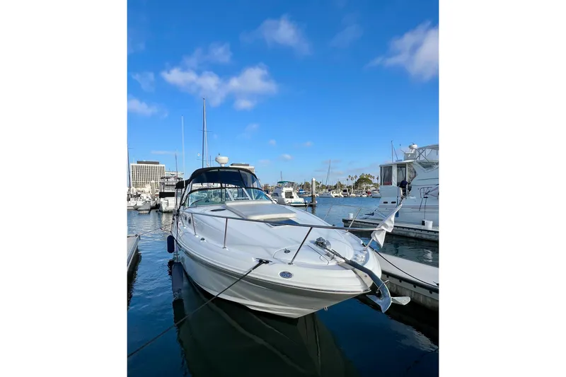 Slide: The Image of 2004 Sea Ray 320 Sundancer yacht docked in a marina under clear blue skies. - 2