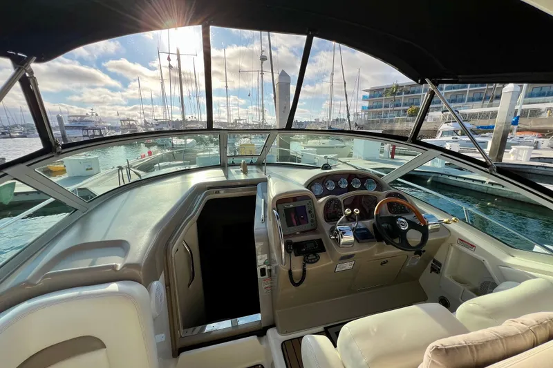 Slide: The Image of 2004 Sea Ray 320 Sundancer cockpit with marina view, featuring helm controls and seating. - 33