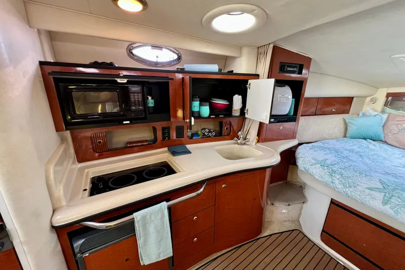 Slide: The Image of 2004 Sea Ray 320 Sundancer interior with kitchenette and cozy sleeping area. - 48