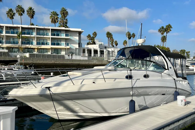 Slide: The Image of 2004 Sea Ray 320 Sundancer docked at marina with modern buildings and palm trees. - 5
