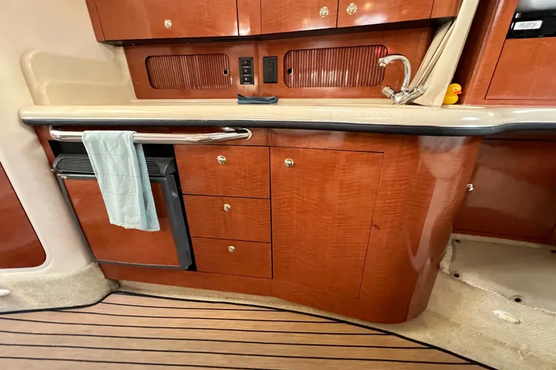 Slide: The Image of 2004 Sea Ray 320 Sundancer interior with wooden cabinetry and compact kitchenette. - 50