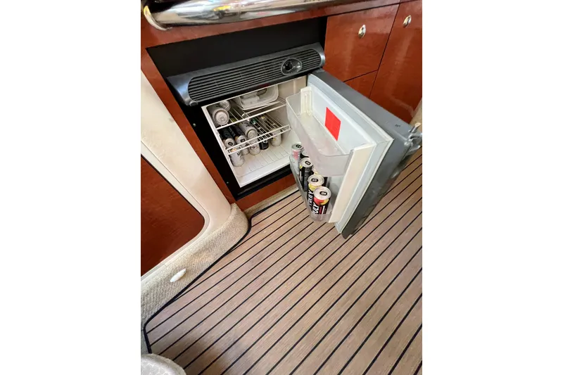 Slide: The Image of 2004 Sea Ray 320 Sundancer interior with open mini fridge and canned drinks. - 52