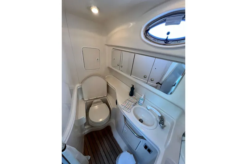 Slide: The Image of 2004 Sea Ray 320 Sundancer bathroom with sink, toilet, and porthole window. - 62