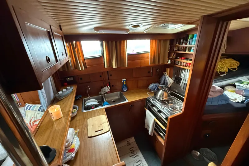 Slide: The Image of Cozy 1980 Nauticat Pilothouse kitchen with wooden cabinetry, stove, and sink. - 11