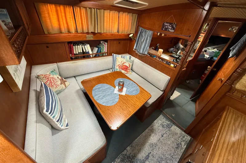 Slide: The Image of 1980 Nauticat Pilothouse interior with cozy seating, wooden table, and nautical decor. - 12