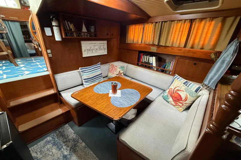 Slide: The Image of Cozy 1980 Nauticat Pilothouse interior with cushioned seating, wooden table, and nautical decor. - 17