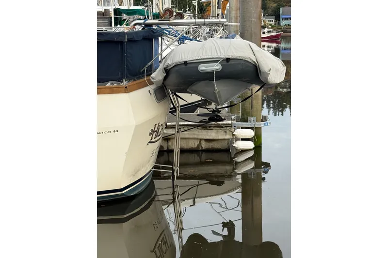 Slide: The Image of 1980 Nauticat Pilothouse yacht docked with covered dinghy, reflecting on calm water. - 21