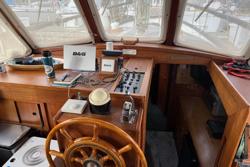 Slide: The Image of 1980 Nauticat Pilothouse interior with wooden helm, navigation equipment, and panoramic windows. - 4
