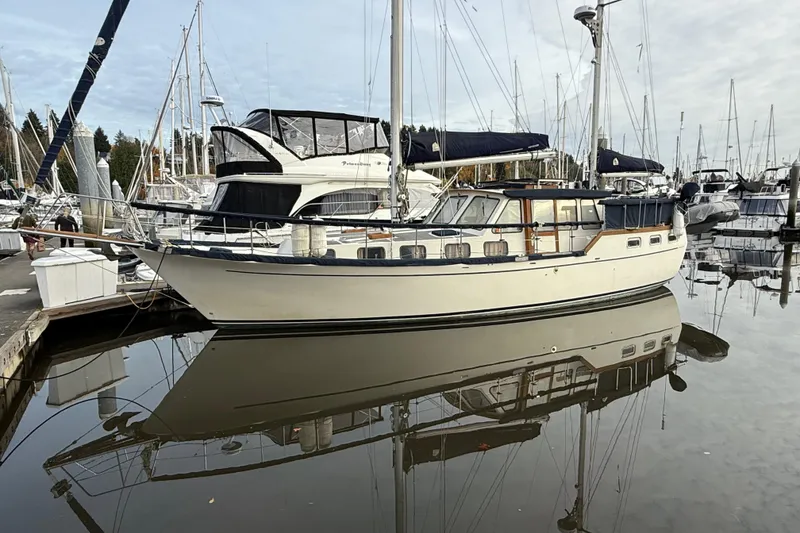 Slide: The Image of 1980 Nauticat Pilothouse sailboat docked in a marina, reflecting on calm water. - 48