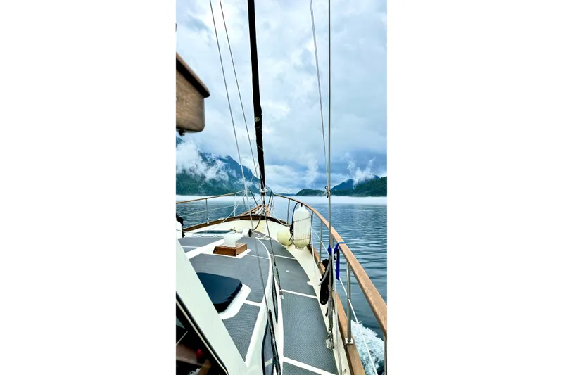 Slide: The Image of 1980 Nauticat Pilothouse sailing on a serene lake with misty mountains. - 50