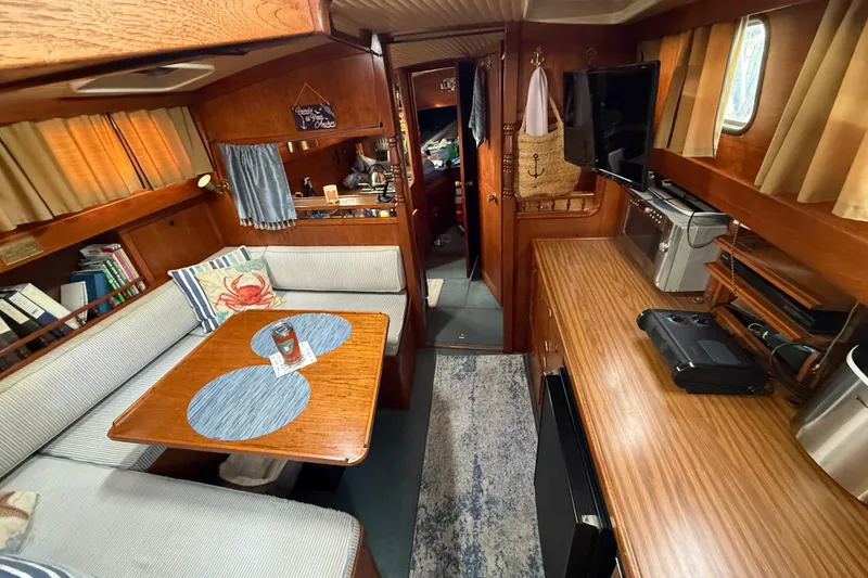 Slide: The Image of 1980 Nauticat Pilothouse interior with cozy seating, wooden table, and modern amenities. - 7