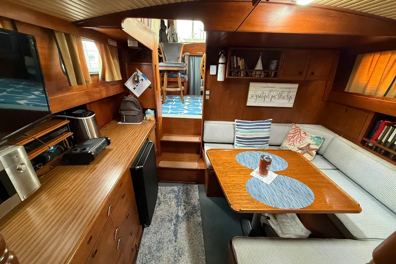 Slide: The Image of 1980 Nauticat Pilothouse interior with cozy seating, wooden cabinetry, and nautical decor. - 9