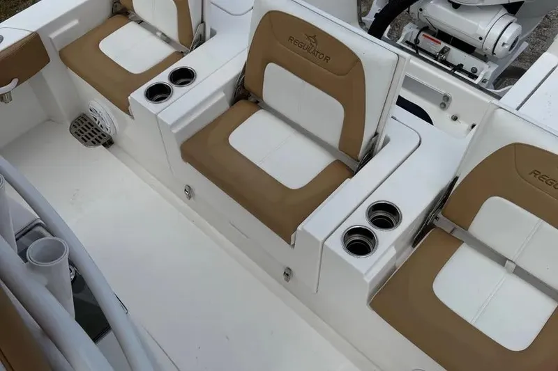 Slide: The Image of 2025 Regulator 26XO boat interior with tan and white seating, cup holders, and motor. - 4