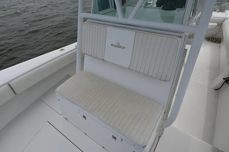 Slide: The Image of 2008 Regulator 32 Forward Seating boat with cushioned bench, white interior, and ocean backdrop. - 11