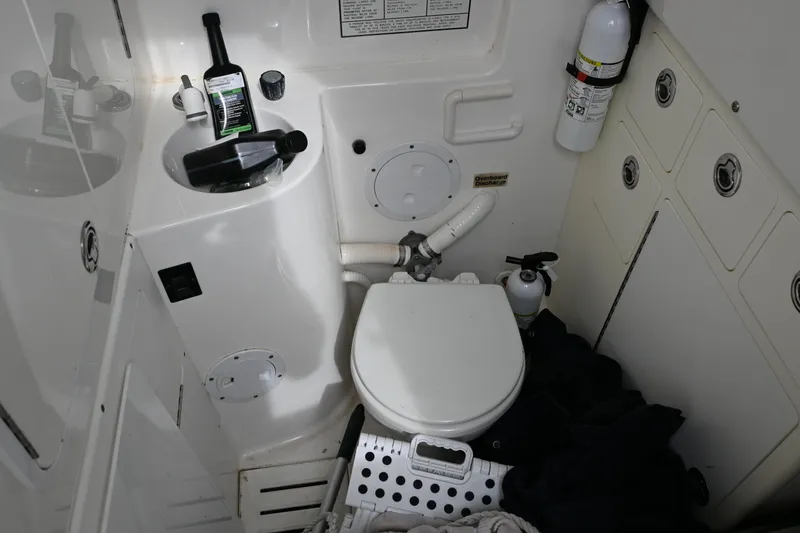 Slide: The Image of 2008 Regulator 32 Forward Seating boat bathroom with toilet, sink, and fire extinguisher. - 19