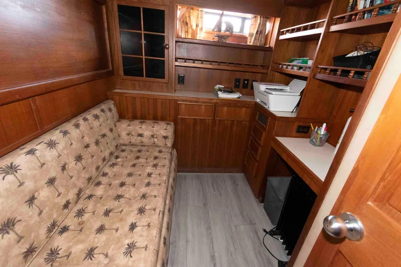 Slide: The Image of 1988 Chris-Craft 46 Constellation interior with wood paneling, sofa, desk, and shelves. - 26