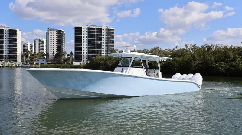 Slide: The Image of 2025 Yellowfin 39 Offshore boat cruising near city skyline and greenery. - 7