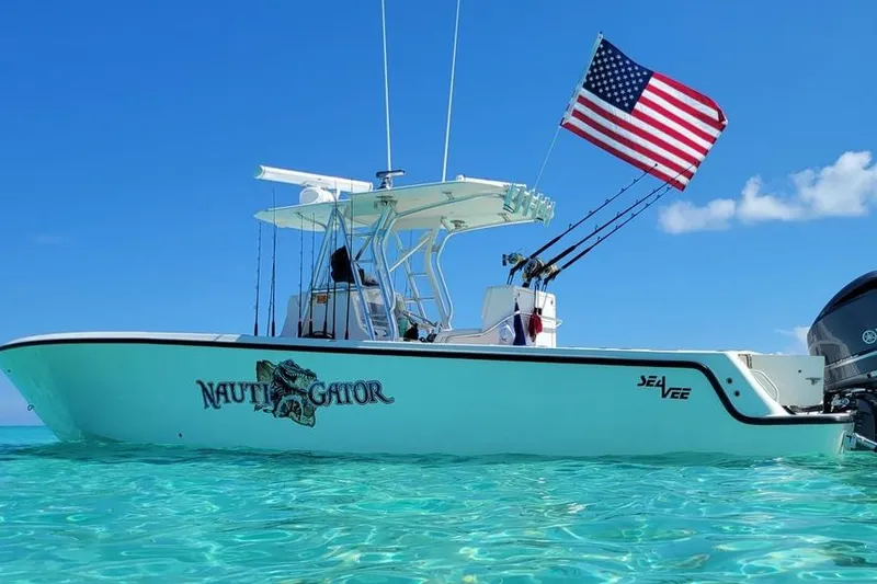 Slide: The Image of 2014 SeaVee 34 boat with American flag, named "Nauti Gator," on clear blue water. - 1