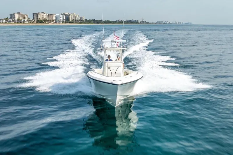 Slide: The Image of 2014 SeaVee 34 boat cruising on open water near coastal cityscape. - 14