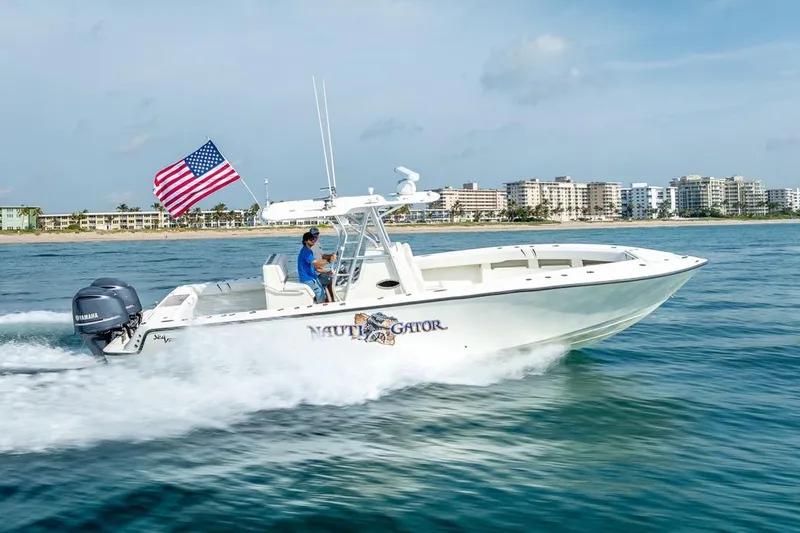 Slide: The Image of 2014 SeaVee 34 boat cruising with American flag, coastal cityscape in background. - 18