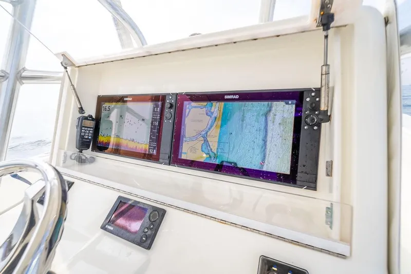 Slide: The Image of 2014 SeaVee 34 boat dashboard with Simrad navigation displays and communication equipment. - 33