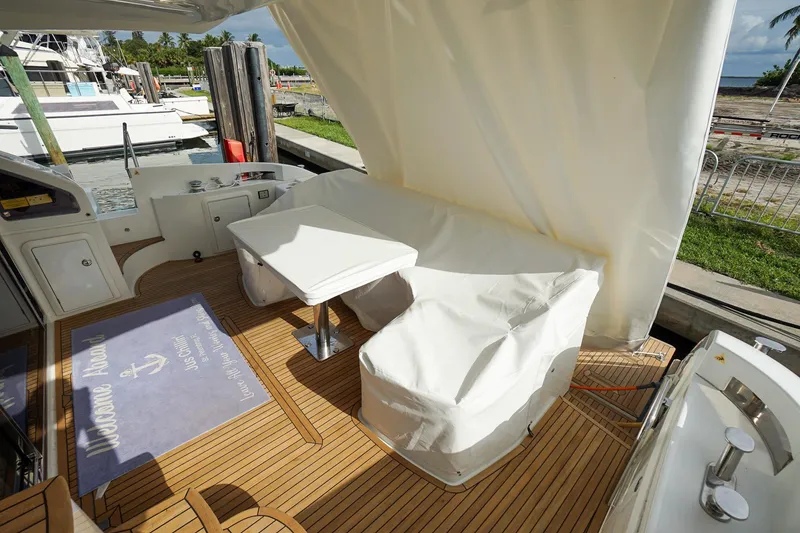 Slide: The Image of Azimut 54 Flybridge 2014 yacht deck with covered seating and table, docked at marina. - 20