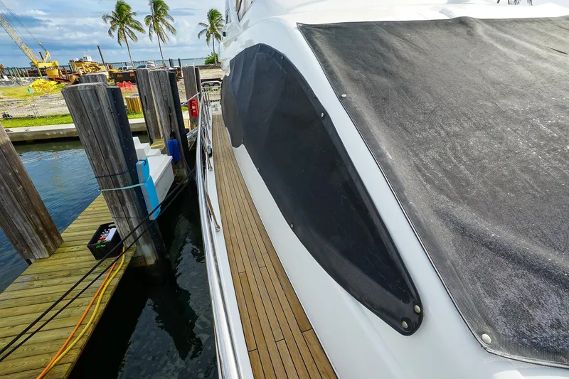 Slide: The Image of 2014 Azimut 54 Flybridge yacht docked, featuring sleek design and wooden deck. - 24
