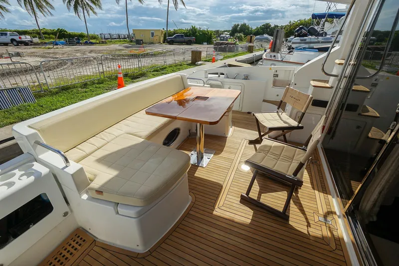 Slide: The Image of Luxurious 2014 Azimut 54 Flybridge yacht deck with seating and table, docked near palm trees. - 59