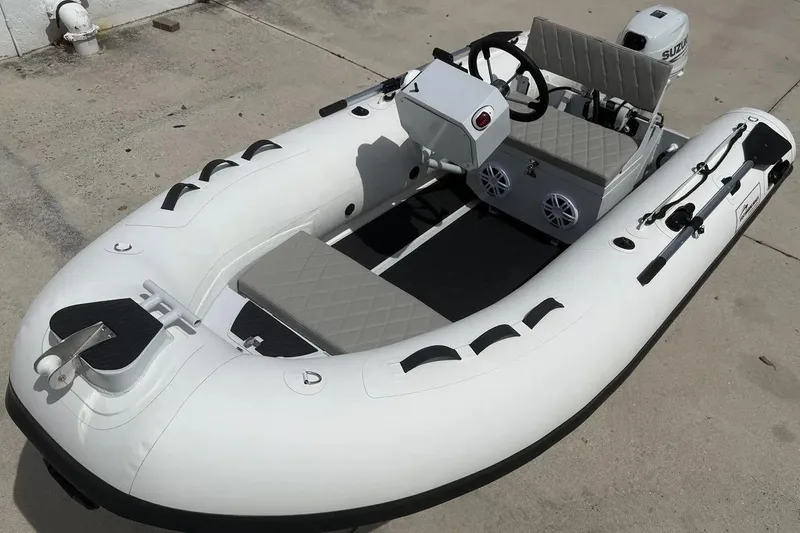 Slide: The Image of Manufacturer Provided Image: 2025 East Marine 320 inflatable boat with steering console and outboard motor on concrete surface. - 3