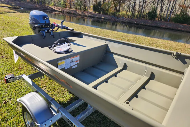 Slide: The Image of 2026 Tracker Grizzly 1436 Utility boat on trailer by a pond, showcasing interior and motor. - 4