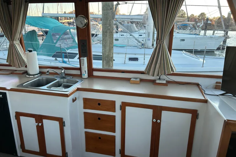 Slide: The Image of Interior of 1991 Holland 38 boat with kitchen sink, cabinets, and marina view. - 12