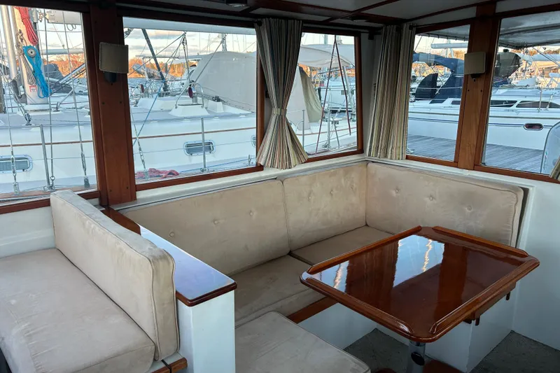 Slide: The Image of Interior of a 1991 Holland 38 boat with cushioned seating and wooden table. - 15