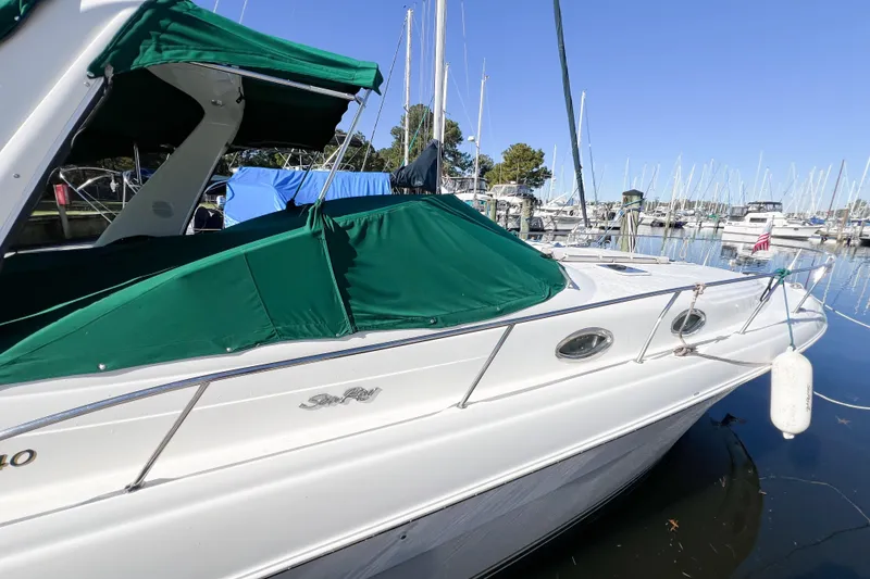 The Image of 2000 Sea Ray 340 Sundancer docked with green canopy, surrounded by sailboats. - 0