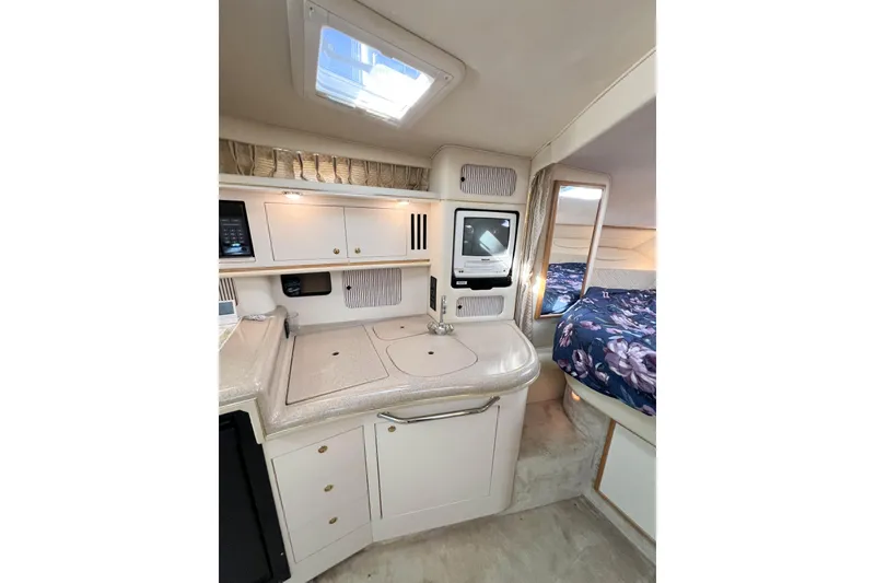 Slide: The Image of 2000 Sea Ray 340 Sundancer interior with kitchenette and cozy sleeping area. - 12