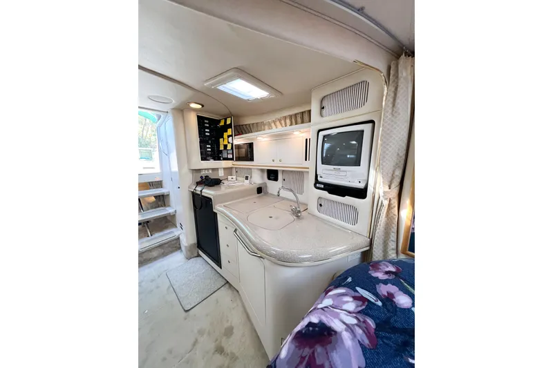 Slide: The Image of Interior of 2000 Sea Ray 340 Sundancer with kitchenette and TV, featuring modern amenities. - 17