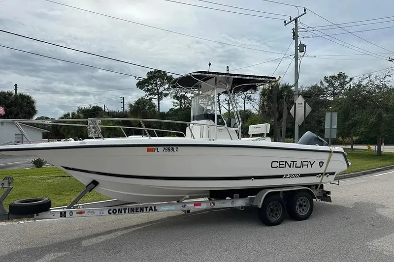 The Image of 2001 Century 2300 Center Console boat on a trailer, parked on a street. - 0
