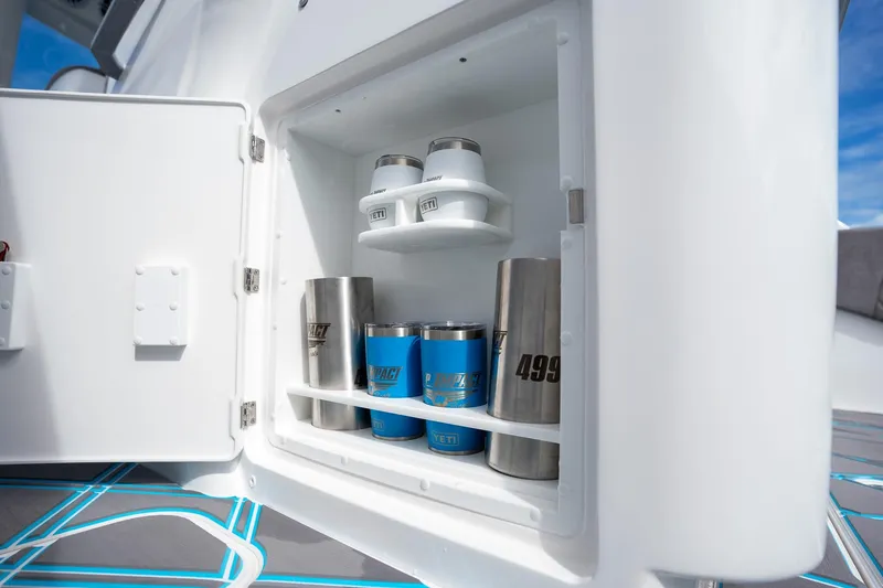 Slide: The Image of Open storage compartment on Deep Impact 499 Sport boat, featuring YETI tumblers and stainless steel cups. - 43