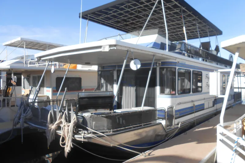 The Image of 1993 Stardust Cruisers 5715 houseboat docked, featuring upper deck and mooring ropes. - 1