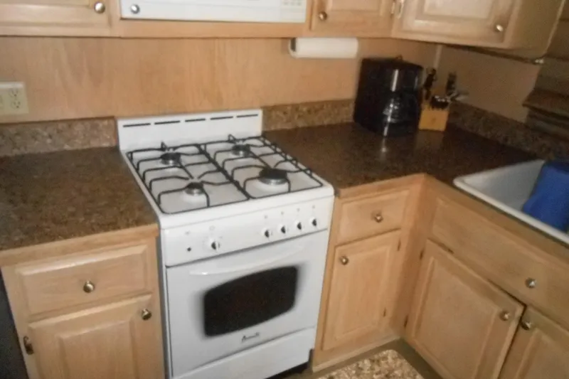 Slide: The Image of 1993 Stardust Cruisers 5715 kitchen with gas stove, wooden cabinets, and countertop appliances. - 16