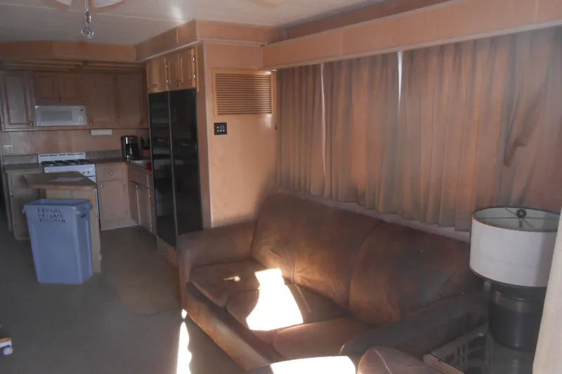 Slide: The Image of Interior of 1993 Stardust Cruisers 5715 with kitchen and living area, featuring brown sofa and curtains. - 3