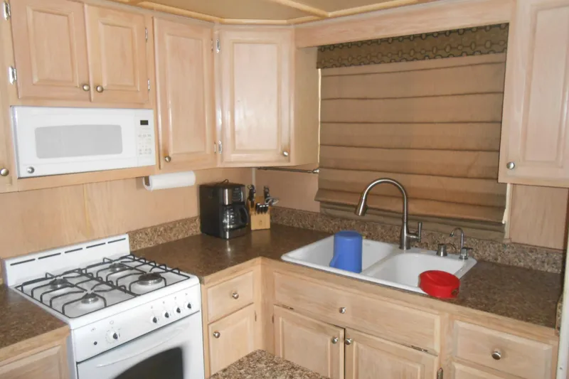 Slide: The Image of 1993 Stardust Cruisers 5715 kitchen with wooden cabinets, gas stove, and dual sink. - 8