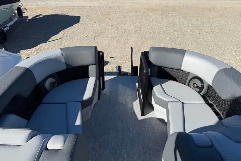 Slide: The Image of 2026 Alera M 23L boat interior with gray seating and speakers, parked on sandy ground. - 15