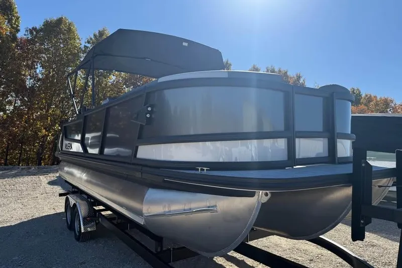 Slide: The Image of Alera M 23L pontoon boat, 2026 model, parked on a trailer under clear blue sky. - 3