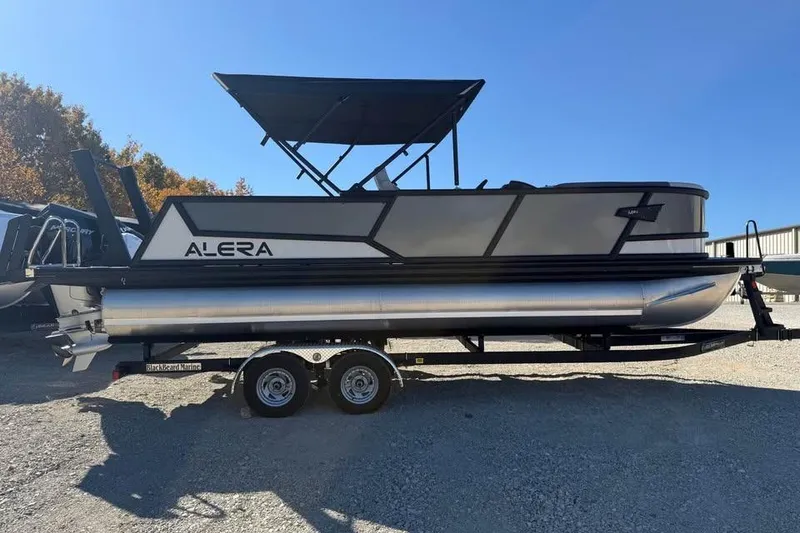Slide: The Image of Alera M 23L pontoon boat, 2026 model, on a trailer under clear blue sky. - 4